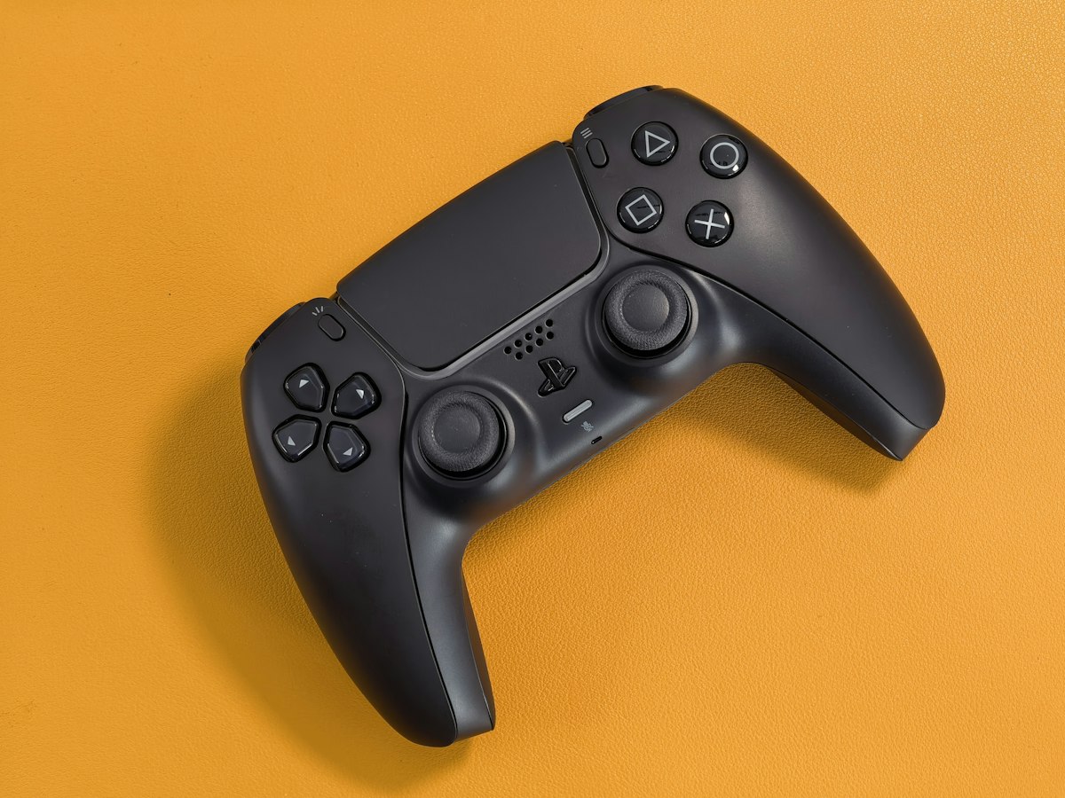 Black game controller on an orange background