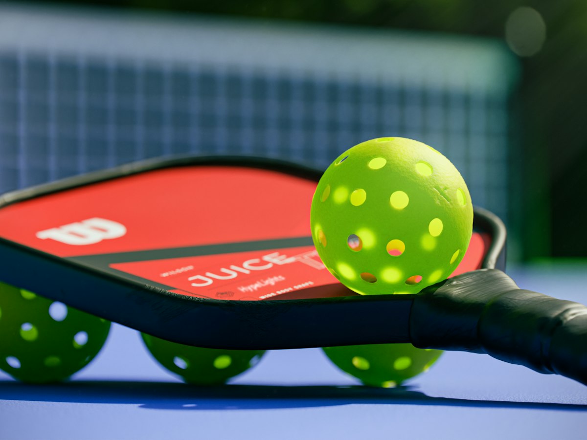 Pickleball paddle and neon balls on a blue court